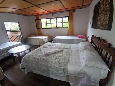 a bedroom with two beds and a table and windows at la casa de mamá in Huayopata
