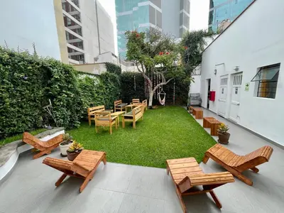 a patio with chairs and tables and a grassy yard at Casaroma Hostels in Lima