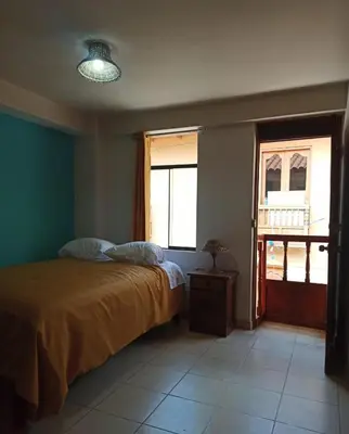 a bedroom with a bed and two windows at Casa D´Maria in Ollantaytambo