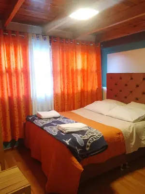 a bedroom with a bed with orange curtains at hostal ollantaytambo apartments in Ollantaytambo