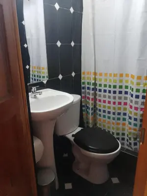 a bathroom with a sink and a toilet with a black lid at hostal ollantaytambo apartments in Ollantaytambo