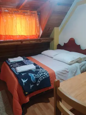 a bedroom with two beds and a table in a room at hostal ollantaytambo apartments in Ollantaytambo
