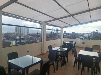 a restaurant with tables and chairs and large windows at HOSTAL SAMAYWASI in Huancayo