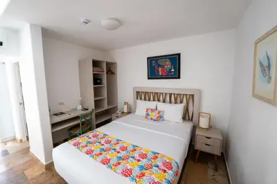 a bedroom with a white bed and a desk at Atoq Paracas Reserva in Paracas