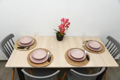 a table with pink plates and a vase of flowers at Departamento Moderno - Zona Exclusiva - Huacachina in Ica