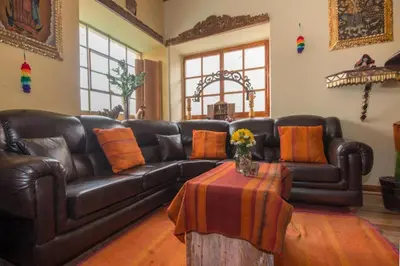 a living room with a leather couch and a table at CASA HOSPEDAJE EL LABRADOR in Cusco