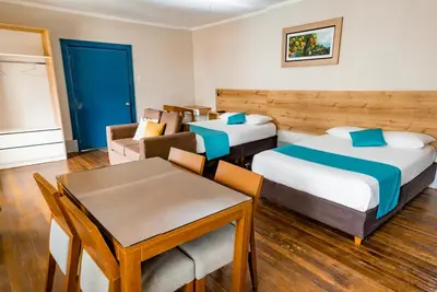 a hotel room with two beds and a table and chairs at Casa Plaza Bolivar in Quillabamba