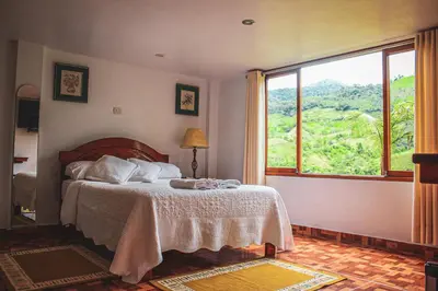 a bedroom with a bed and a large window at Albergue Turístico Gstir in Pozuzo