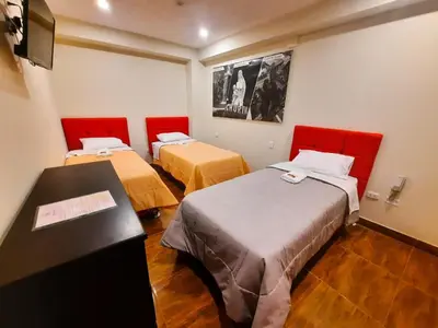 a room with two beds and a desk in it at Brianny Hotel in Churín