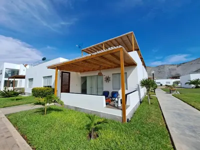 a white house with two chairs in the yard at Alquilo casa de playa Condominio Playa Azul cerca de Asia in Cerro Azul