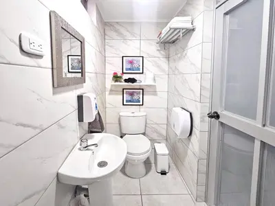 a white bathroom with a toilet and a sink at Hospedaje Celerina & Elio in Lima