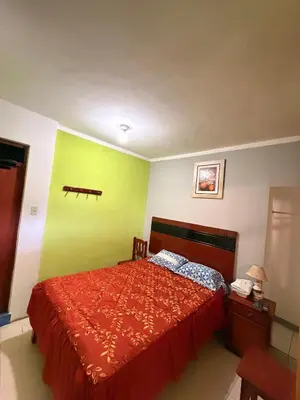 a bedroom with a red bed and a green wall at HOSTAL GRAU in Churín