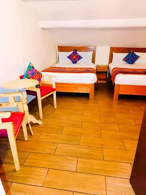 a room with two beds and a table and chairs at Hotel Ecoterra Andino Cusco in Cusco