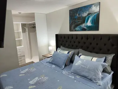 a bedroom with a bed with a blue comforter and pillows at 595 Departamento en Chorrillos in Lima