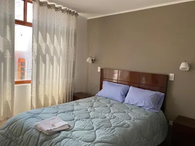 a bedroom with a large bed with blue pillows and a window at EL GRAN SEÑORIAL in Jauja