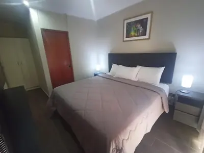 a large bed in a hotel room with two lamps at Hotel Nebai in Ica