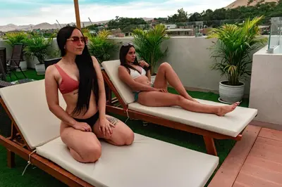 two women in bathing suits sitting on chairs on a balcony at Hotel Nebai in Ica